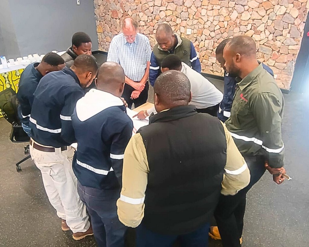 Comodex delegates in hi-visibility workwear working through a group exercise around a table during an in-company training session